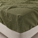 Moss green linen fitted sheet corner with elasticated edge on beige bed