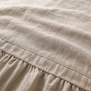 Oat linen fitted sheet close-up with ruffled elastic edge and textured weave